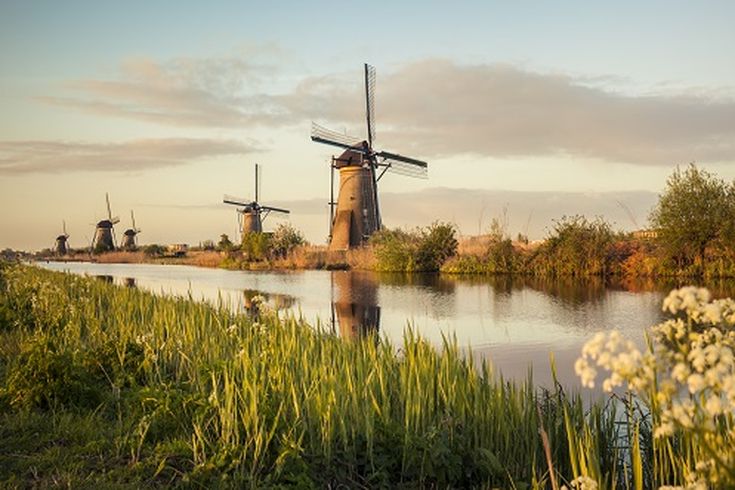 Eine Windmühle am Flussufer mit einem Boot.
