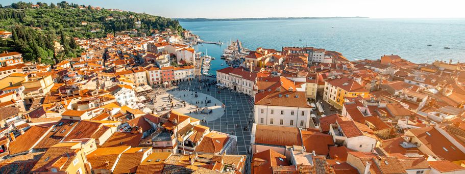 Eine Stadtansicht von Piran, Slowenien, mit roten Dächern und Blick auf das Meer.