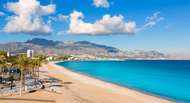 Ein Sandstrand mit einem flachen Meer und einem blauen Himmel.