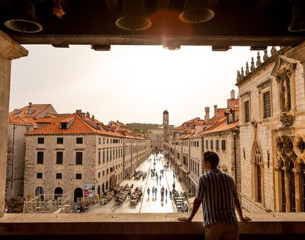 Ein Mann schaut aus einem Ruinenfenster auf Stradun, die Straße in Dubrovnik.