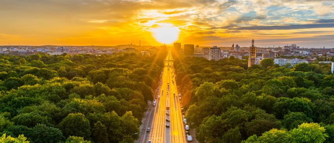 Sonnenuntergang über dem Tiergarten in Berlin, fotografiert von der Siegessäule aus mit Blick auf die Straße des 17. Juni Richtung Brandenburger Tor.