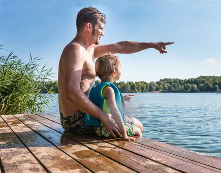 Vater sitzt mit Sohn auf Steg