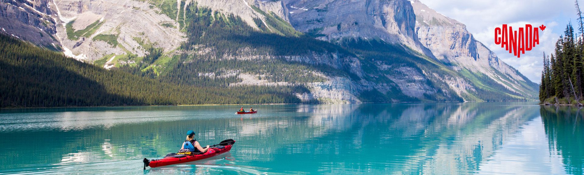 Kanufahrerin im roten Kanu auf dem türkisblauem Lake Maligne vor den sagenhaften Rocky Mountains