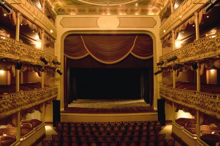 Die Bühne eines Theaters mit roten Samtvorhängen.