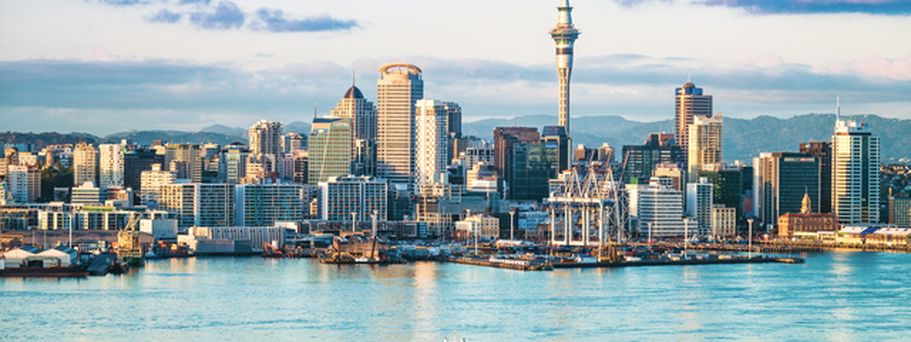 Die Skyline von Auckland, Neuseeland, mit Gebäuden am Wasser und dem Sky Tower.