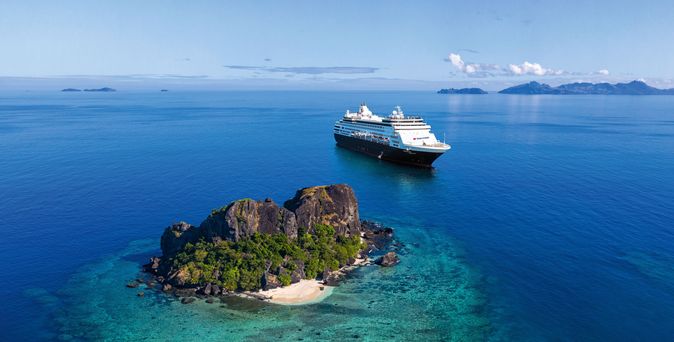 Kreuzfahrtschiff fährt durch das Meer mit grüner Insel im Vordergrund