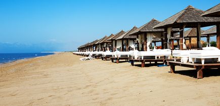 Strandansicht in Antalya, Türkei, mit einer Reihe von luxuriösen Cabanas und Liegen, die sich entlang des Sandstrandes erstrecken, mit dem Meer am Horizont.
