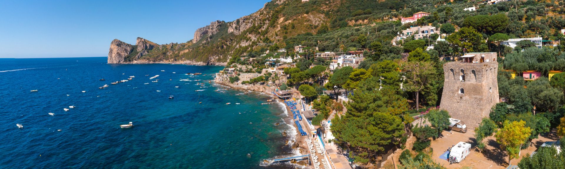 Luftaufnahme des felsigen Strandes, Küste des Dorfes Nerano. Private und wilde Strände. Türkisblaue, blaue Wasseroberfläche. Urlaubs- und Reisekonzept. Alter Turm und Campingplatz für Wohnmobile