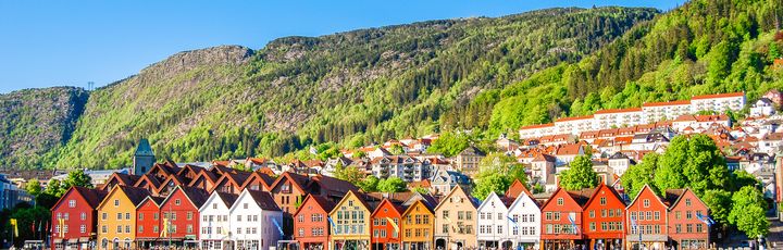 Zu sehen sind die farbenfrohen Häuser Bergens. Direkt am Wasser gelegen, jedes Haus eine andere Farbe. Kleines Bötchen liegt an Land.