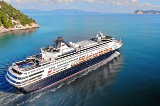 Kreuzfahrtschiff fährt durch das Meer mit grünen Bergen im Hintergrund