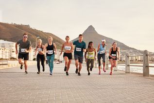Eine Gruppe Marathonläufer und Läuferinnen läuft vor dem Tafelberg in Kapstadt