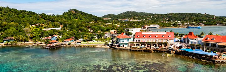 Blick auf die Paradiesische Küste von Roatan, Honduras mit bunten Häusern am Hafen