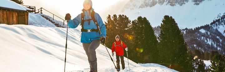 Zwei Personen in Skikleidung, die auf Langlaufskiern unterwegs sind.