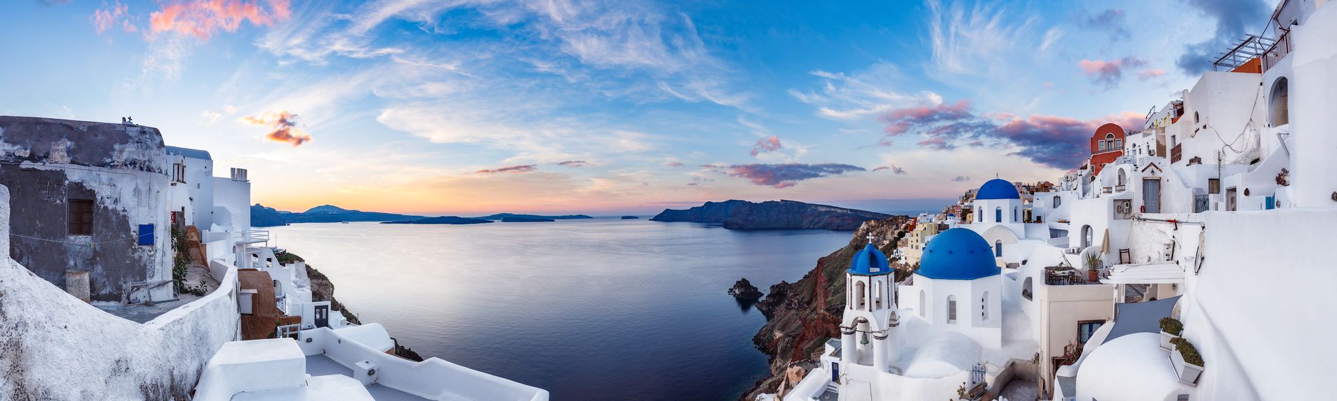 Blick auf weiße Häuser mit blauen Dächern mit Meer im Hintergrund