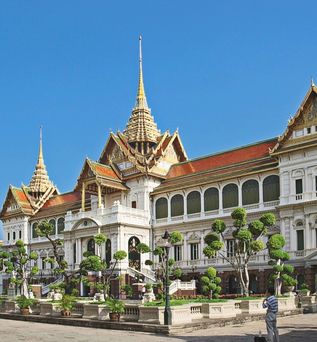 Ein großes, weißes, palastartiges Gebäude mit einem grünen Rasen im Vordergrund.