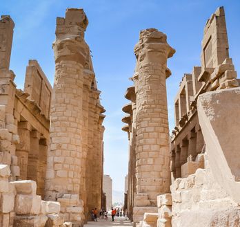 Eine archäologische Stätte in Luxor, die von einer großen Säulenreihe und alten Strukturen umgeben ist.