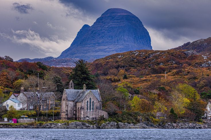 Blick auf einen kleinen Ort mit dem großen Berg Suilven.