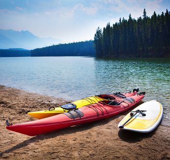 zwei Kanus und ein Surfboard an einem See