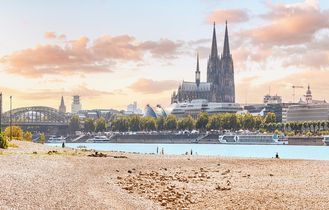 Eine Stadtansicht mit einem Dom und einem Fluss bei Sonnenuntergang.