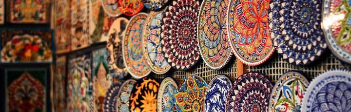Detailreich bemalte Keramikteller in leuchtenden Farben schmücken die Wand eines kunstvollen orientalischen Marktes.