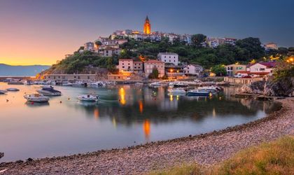 Eine Hafenstadt mit Booten und beleuchteten Gebäuden bei Sonnenuntergang.