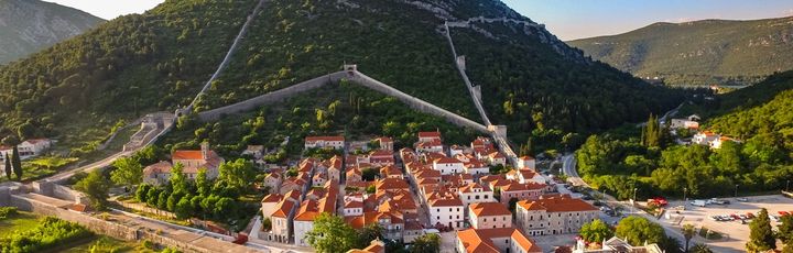 Eine Stadtansicht mit roten Dächern und Bergen.