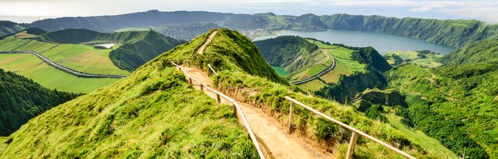 Eine grüne, hügelige Landschaft mit einem Pfad, der sich durch die Hügel schlängelt.