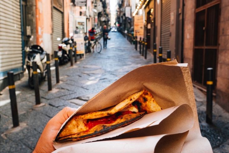 Eine Person hält ein Stück Pizza.