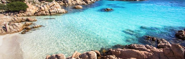 Die idyllische Cala Coticcio auf La Maddalena, Sardinien, Italien, mit türkisfarbenem Wasser, weißem Sand und felsigen Buchten, umgeben von mediterraner Vegetation.