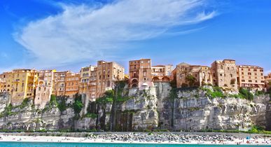 Eine malerische Stadt, die auf steilen Klippen über einem türkisfarbenen Meer thront, mit einem Strand am Fuße der Klippen.