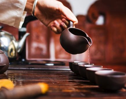 Zubereitung von japanischem Tee in traditionellen Keramikgefäßen – Ein Gastgeber gießt mit ruhiger Hand duftenden Tee in kleine Schalen – ein Moment echter Achtsamkeit.