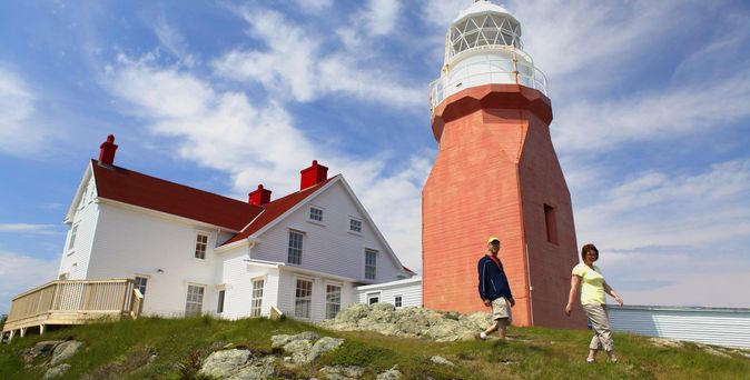 Long Point Leuchtturm in Twillingate. Auf einem Hügel, der Leuchtturm ist unten braun gehalten mit weißer Spitze. Daher ein weißes Gebäude mit rotem Dach.