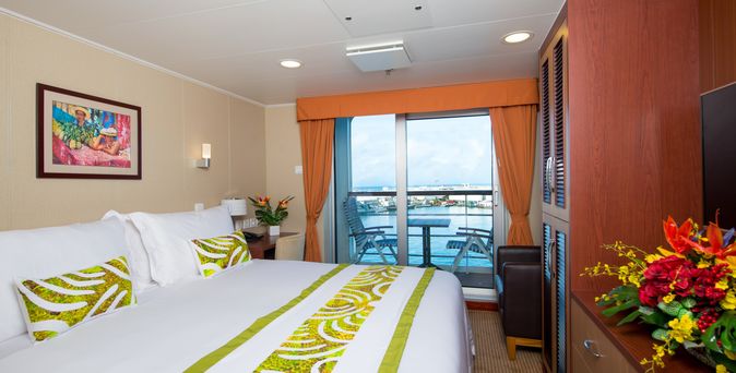 Eine luxuriöse Schiffskabine mit einem großen Bett und einem Balkon.