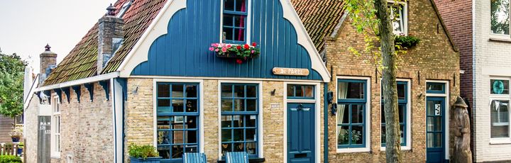 Ein blaues Haus mit einem Garten und einem Zaun.