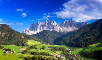 Malerisches Tal in der Steiermark mit grünen Wiesen und bewaldeten Hängen, umgeben von majestätischen Bergen.