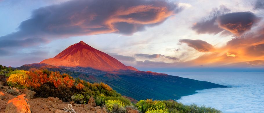 Eine vulkanische Landschaft mit einem Berg bei Sonnenuntergang.