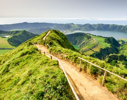 Eine grüne, hügelige Landschaft mit einem Pfad, der sich durch die Hügel schlängelt.