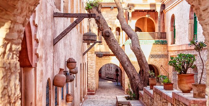 Eine enge, gepflasterte Gasse in einer Medina mit bunten Geschäften.