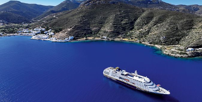 Kreuzfahrtschiff fährt durch das Meer mit Berg im Hintergrund