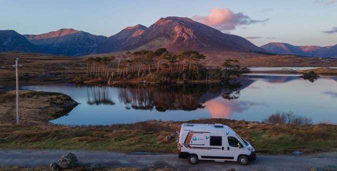 Wohnmobil steht an einem See im Connemara National Park, Galway in Ireland. So langsam tritt die Abenddämmerung ein und der Himmel verfärbt sich leicht rosa