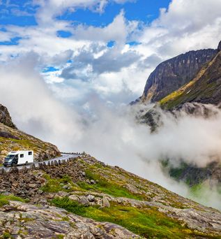 Grünes Tal mit Fluss und sprudelnden Wasserfällen in Norwegen, umgeben von hohen Bergen.