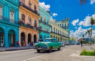 Grüner Oldtimer fährt auf der Hauptstraße in Havanna Stadt Kuba an der historischen Häuserfront vorbei