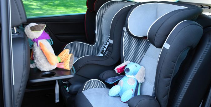 Blick auf die Rückband eines Autos, mit Kindersitzen und Kuscheltieren.