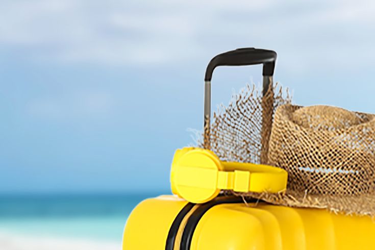 Gelber Koffer am Strand.