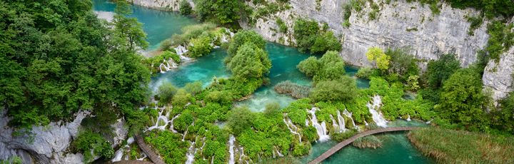 Ein großer Wasserfall, der in mehrere Stufen über Felsen fließt, umgeben von üppiger Vegetation.