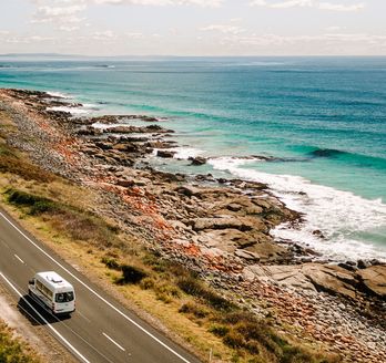 Camper fährt entlang einer Straße am Meer in Australien 
