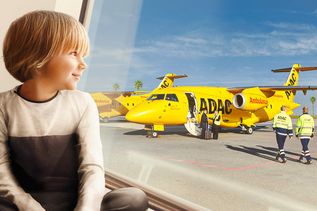 Kind guckt auf das Rollfeld wo ein ADAC Flugzeug steht