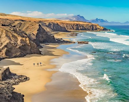 Ein Sandstrand mit Felsen und Meer.