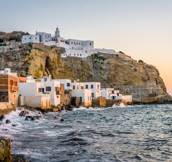 Schroffe Küste, davor kleine Häuser, oben auf dem Felsen ist das Kloster zu sehen.