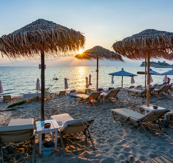 Sonnenuntergang am Siviri Strand. Liegen, Sonnenschirme und Schwimmer.